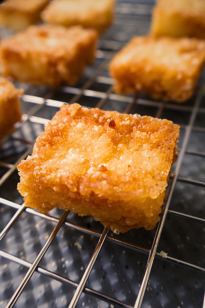 Golden crispy sushi rice squares cooling on a wire rack after frying, ready to be topped with spicy tuna and Japanese mayonnaise.