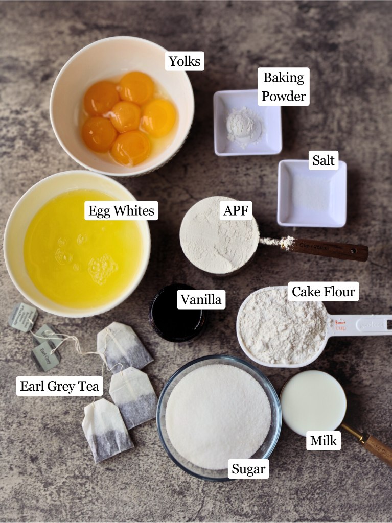 Ingredients for homemade Earl Grey tres leches cake arranged on a countertop, including egg whites, egg yolks, flour, sugar, milk, Earl Grey tea, baking powder, vanilla, and salt.