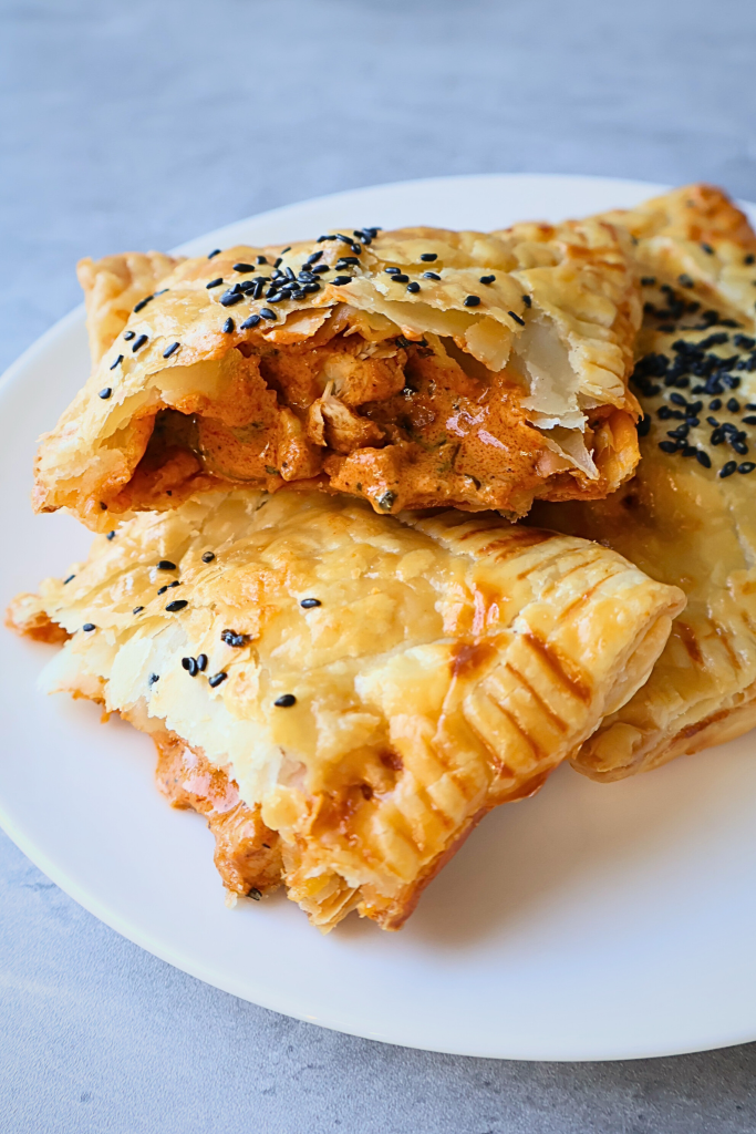 Golden, flaky phyllo pastry pockets filled with creamy butter chicken, baked until crisp and topped with black sesame seeds.