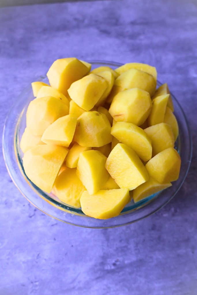 Bowl of peeled and chopped potatoes, ready for making creamy French aligot or homemade mashed potatoes.