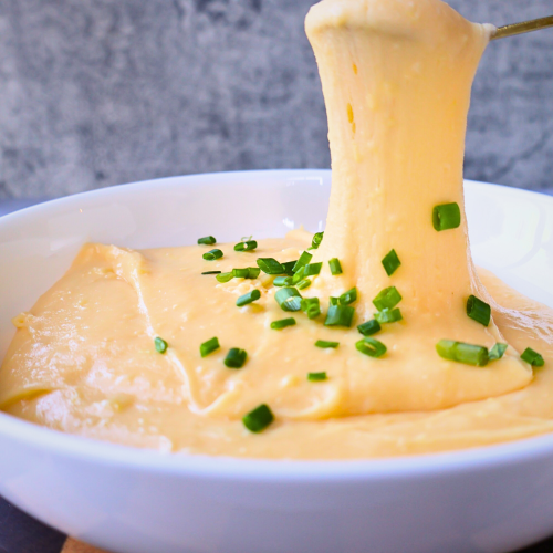 Stretchy French aligot mashed potatoes topped with chopped chives in a serving bowl.