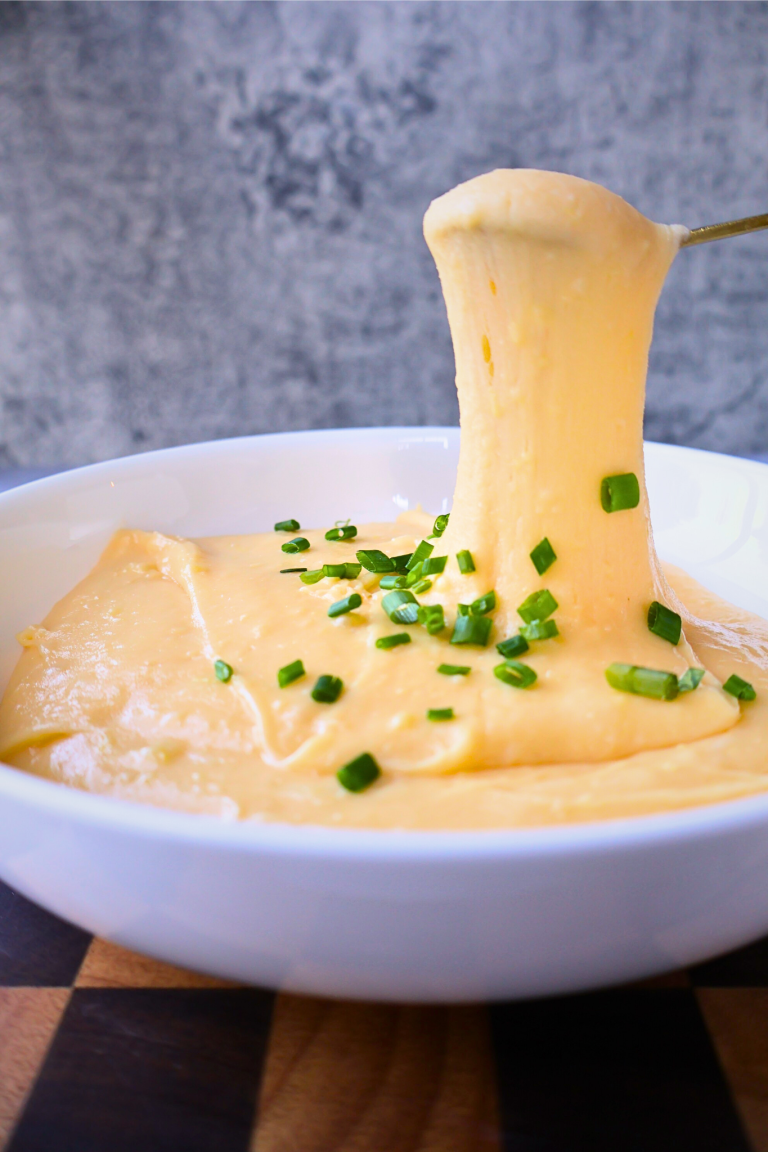 Stretchy French aligot mashed potatoes topped with chopped chives in a serving bowl.