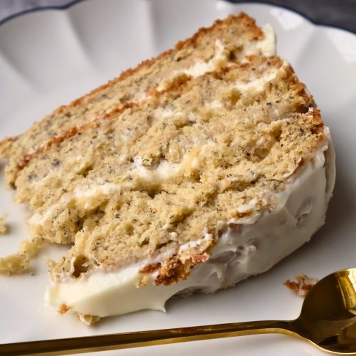 Close-up of a moist four-layer banana cake with creamy cream cheese frosting, showing the fluffy texture and rich banana color.