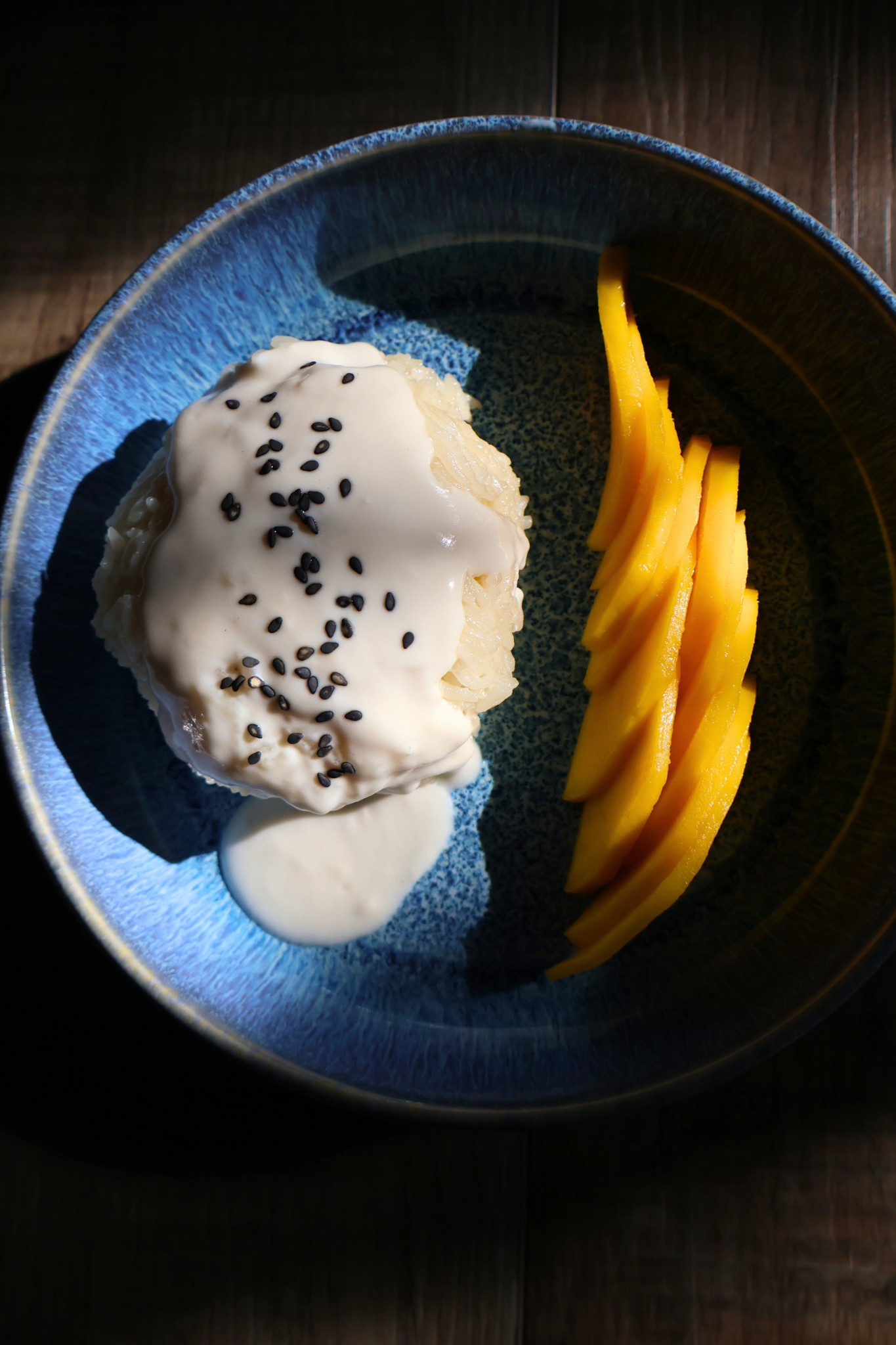 Thai mango sticky rice with coconut cream and black sesame seeds served with fresh sliced mango