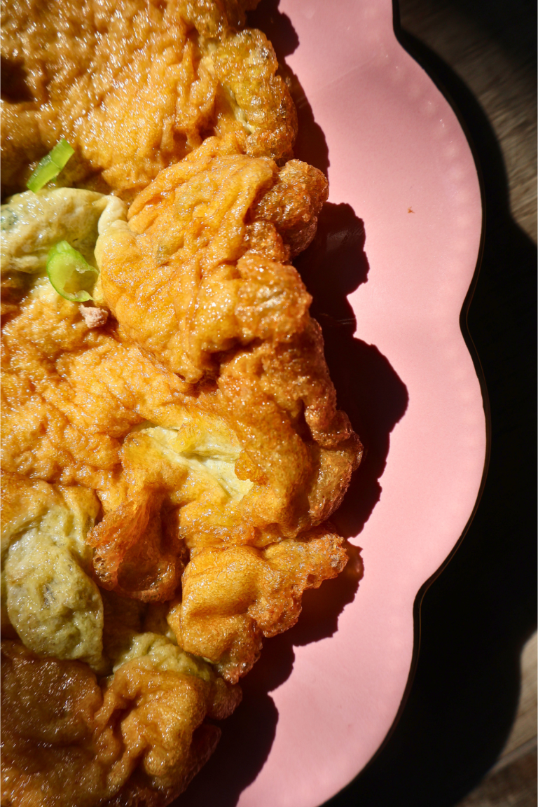 Close-up of crispy Thai omelet with golden edges in pink bowl
