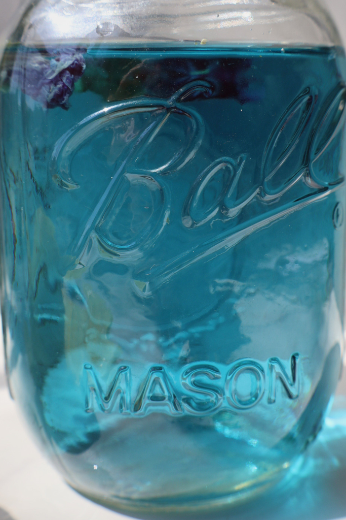 Blue butterfly pea tea in a glass mason jar before adding lemon