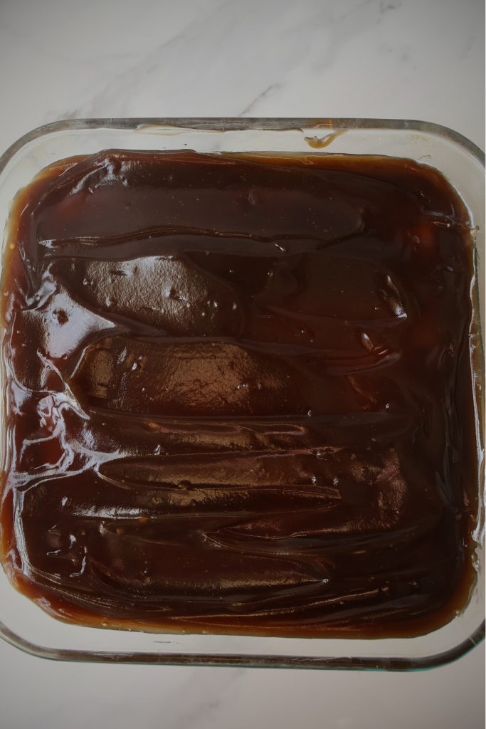 Balkan trilece cake in baking dish topped with glossy caramel glaze