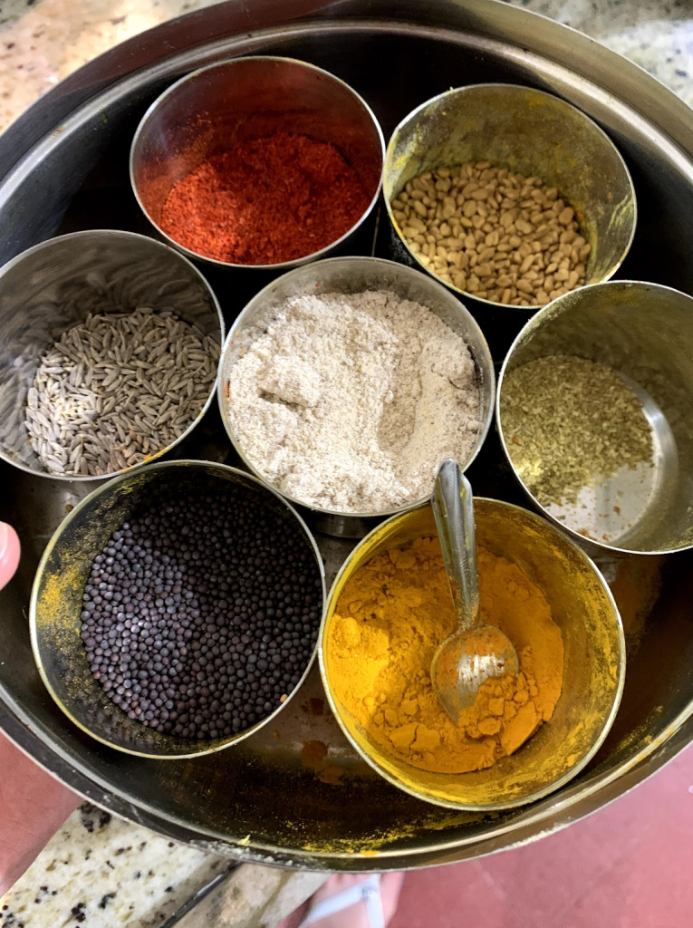 Mrigakshi's masala dabba in Mumbai filled with Indian spices including turmeric, red chili powder, mustard seeds, and flour — the first masala dabba I ever saw