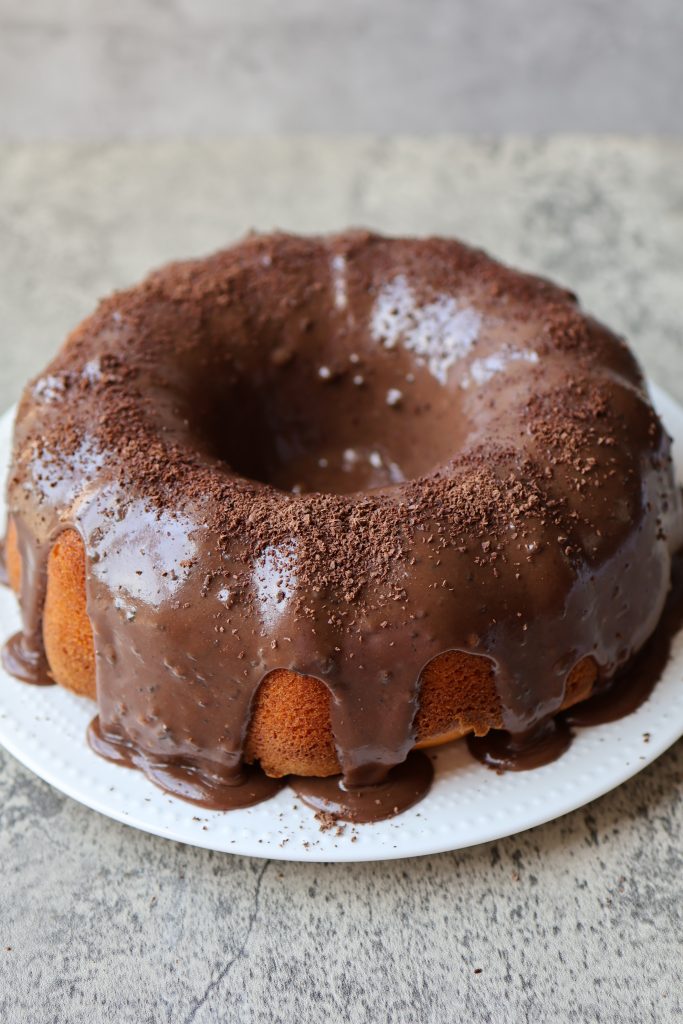 Brazilian carrot cake (bolo de cenoura) with shiny chocolate glaze on a white plate