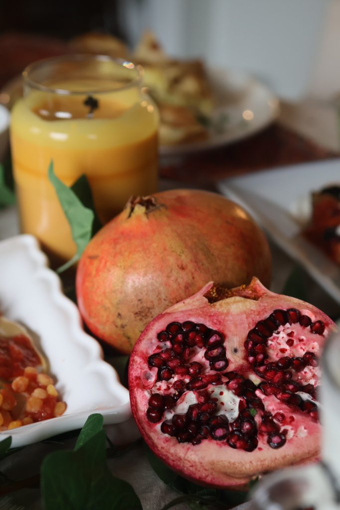 Fresh pomegranate cut open on an Afghan dining table, showcasing its ruby-red seeds alongside traditional Afghan dishes.