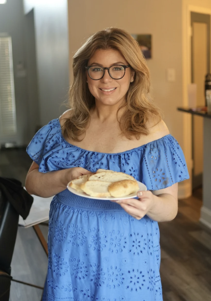 Emilia Kim holding a plate of homemade pita at her Greek table for Hosting the World
