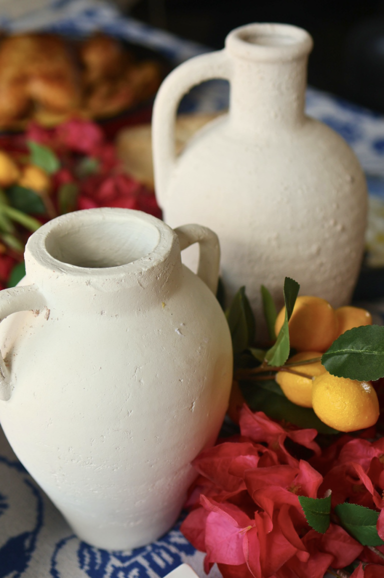 White ceramic vases with fresh flowers and lemons styled on a Greek table for an Aegean look
