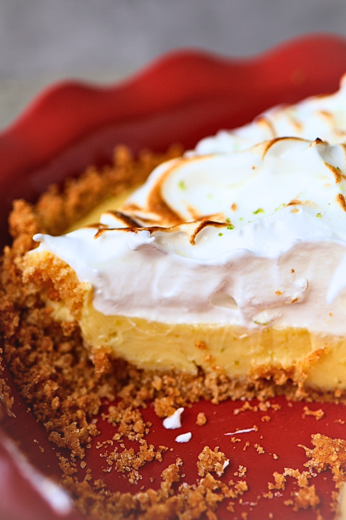 Close-up side view of a key lime pie slice showing graham cracker crust, key lime filling, and toasted meringue layers