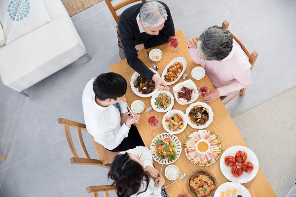 Family enjoying a Korean meal together around a table filled with traditional Korean dishes and side dishes.