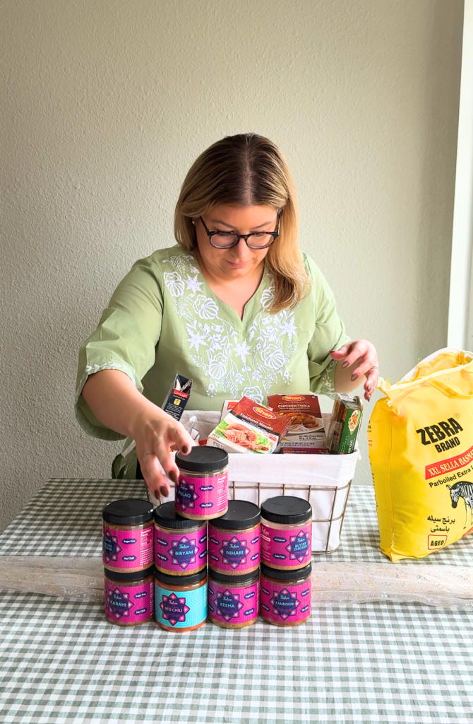 Emilia Kim preparing ingredients for a Hosting the World episode, arranging colorful products and food items on a checkered table.
