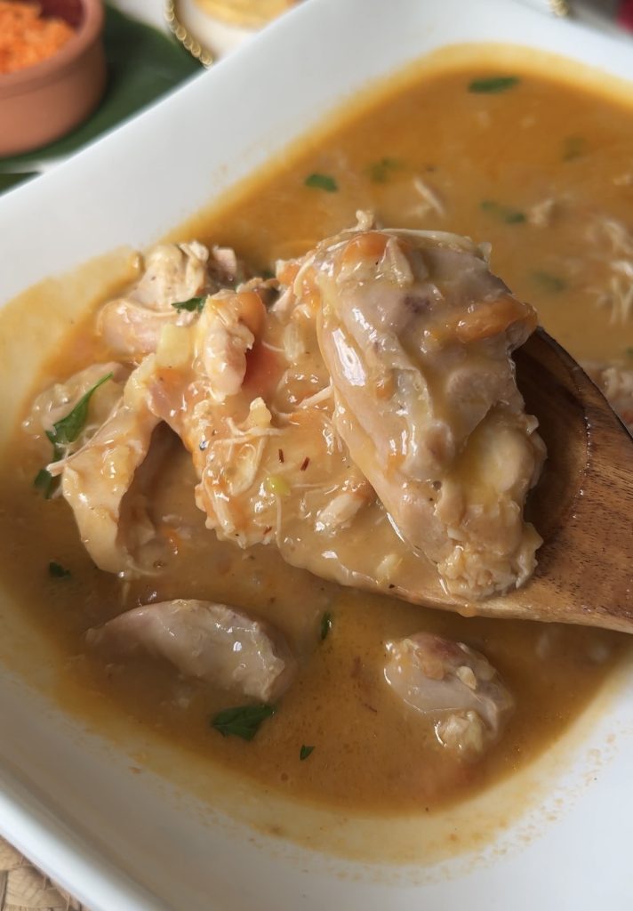 Akoho sy Voanio, a traditional Malagasy chicken stew made with coconut milk and tomatoes, served in a rich and creamy sauce.