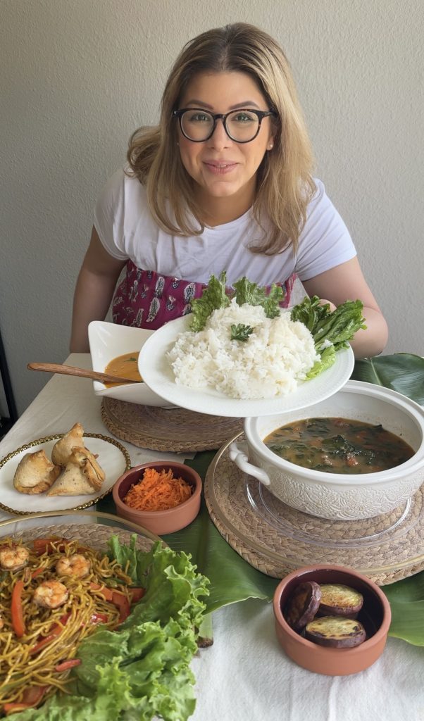 Emilia Kim hosting a Madagascar-inspired dinner, presenting a plate of steamed white rice alongside traditional Malagasy dishes including romazava, mine sao, lasary, and koba.