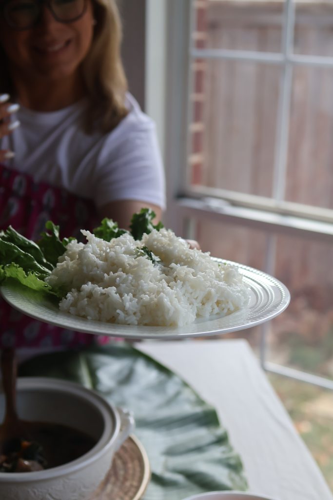 Serving steamed white rice alongside traditional Malagasy dishes during a Madagascar-inspired Hosting the World dinner.