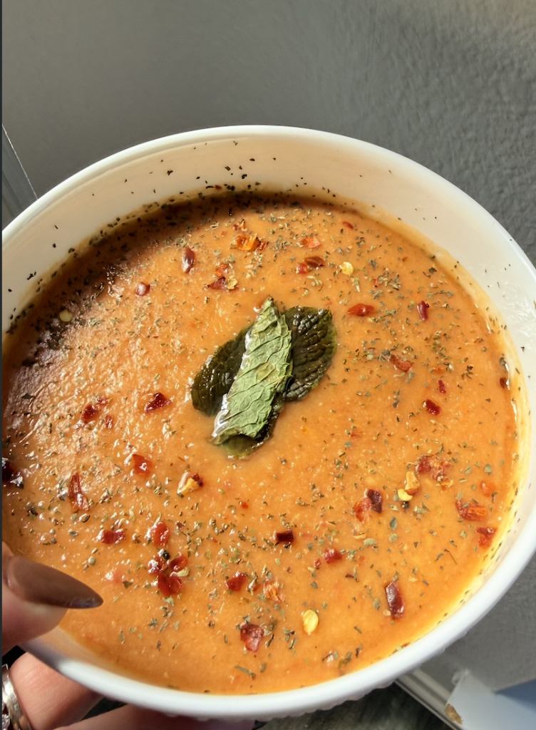 Creamy Turkish red lentil soup garnished with mint and red pepper flakes in a white bowl.