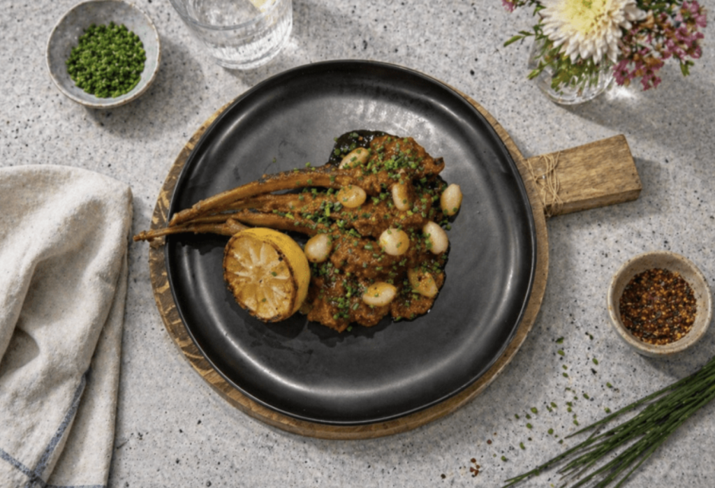 Pakistani-style lamb chops masala served on a black plate with aromatic spices and garnishes.