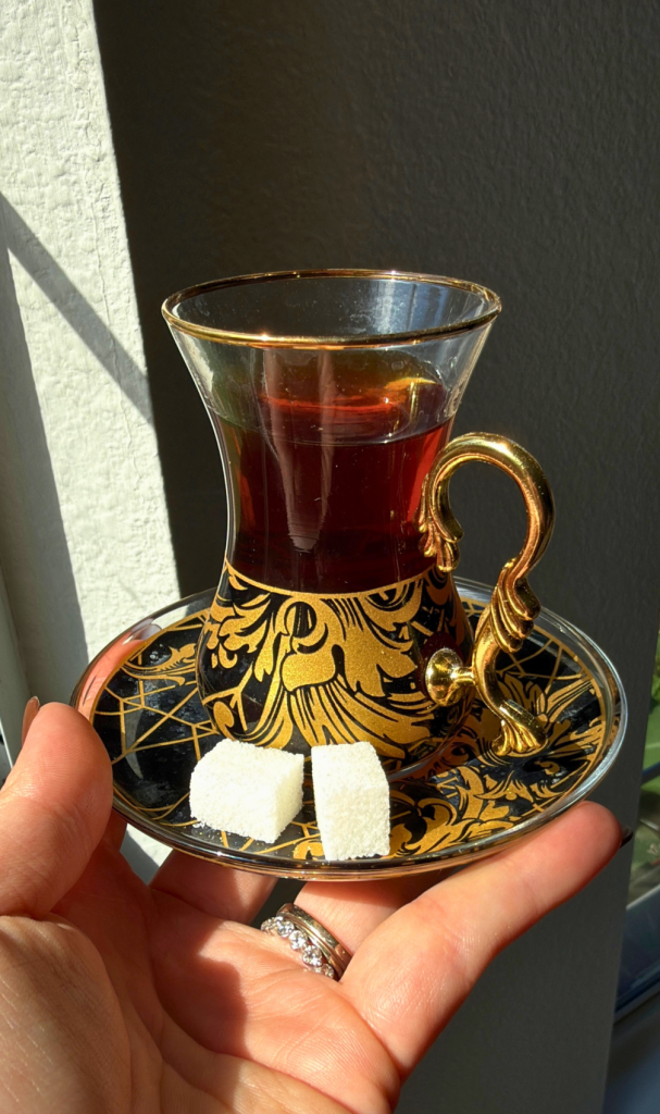 Traditional Turkish tea served in an ornate glass cup with sugar cubes on a decorative saucer.