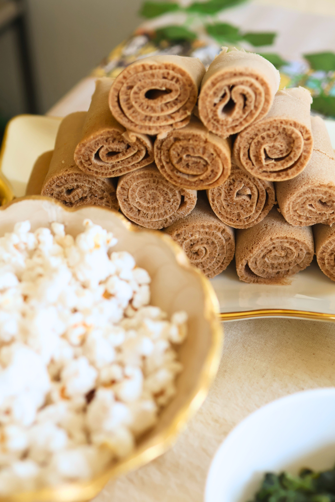 Traditional Ethiopian injera rolls served on a platter with popcorn and side dishes.