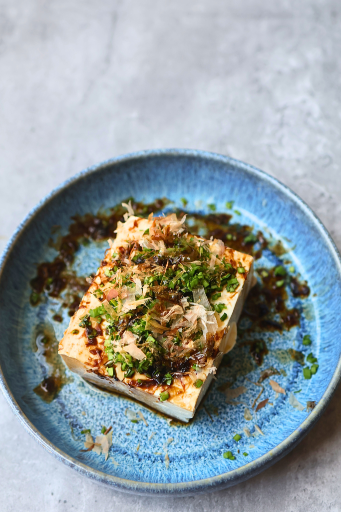 Traditional Japanese hiyayakko made with chilled silken tofu topped with bonito flakes, scallions, and soy sauce.