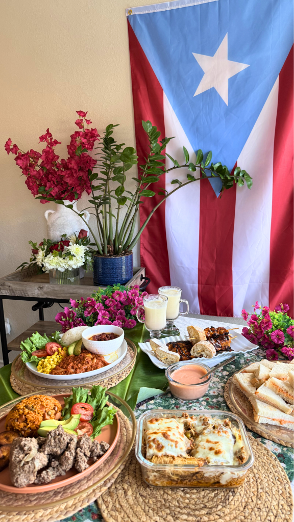 Puerto Rican feast featuring pastelón, arroz con gandules, white rice with stewed beans, bistec encebollado, sandwichitos de mezcla, grilled pinchos, piña coladas, and traditional side dishes displayed on a festive table with a Puerto Rican flag.