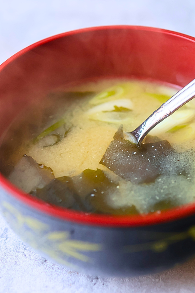 Traditional Japanese miso soup with tofu, wakame seaweed, and green onions served in a lacquer bowl.