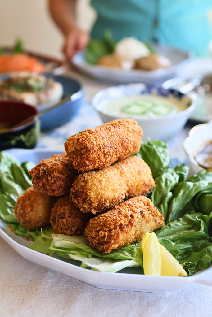 Traditional Japanese korokke served on a bed of lettuce with a lemon wedge.