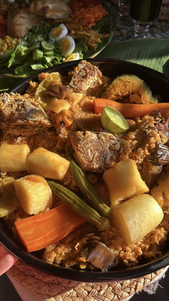 Close-up of traditional Senegalese thieboudienne served with seasoned rice, fish, cabbage, carrots, cassava, eggplant, okra, and other slow-cooked vegetables in a large serving platter.