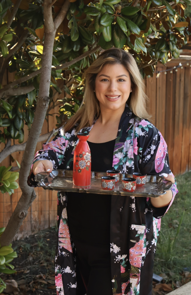 Emilia Kim wearing a Japanese happi-style coat while presenting a tray of homemade Japanese dishes for Hosting the World Japan.