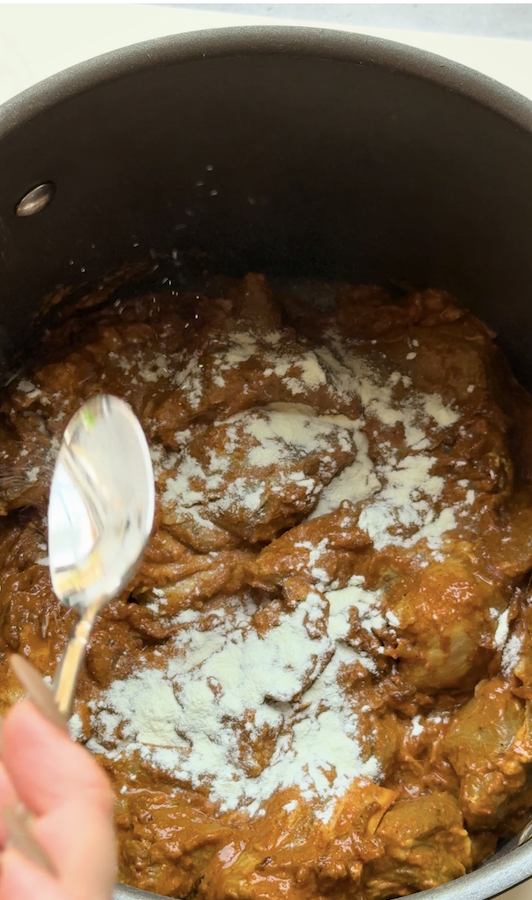 Close-up of marinated mutton for authentic Bangladeshi kacchi biryani topped with milk powder before layering and traditional dum cooking.