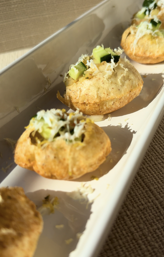 Close-up of crispy Bangladeshi fuchka filled with a seasoned potato mixture, cucumber, fresh herbs, and grated egg, served on a white platter.