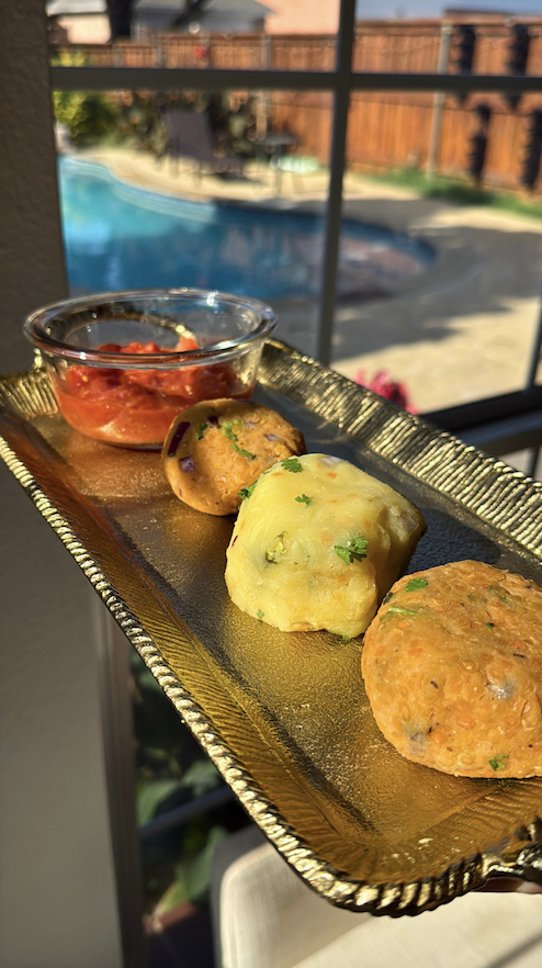 A traditional Bangladeshi bhorta platter featuring two lentil bhorta, one potato bhorta, and one tomato bhorta served on a gold tray with a side of tomato chutney.