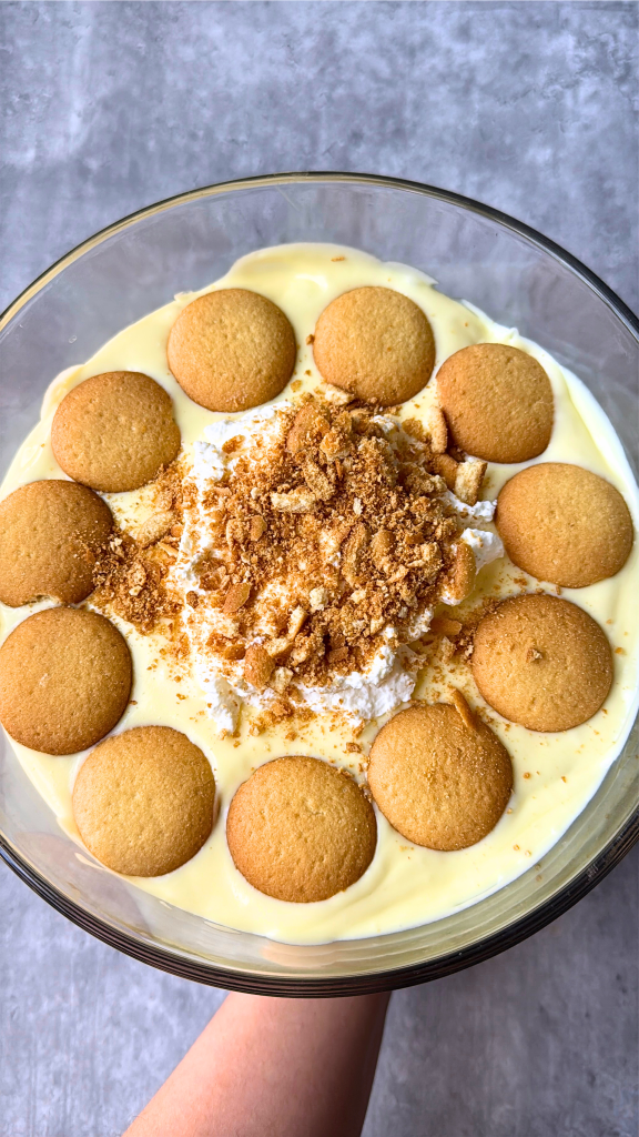 Homemade Southern banana pudding topped with vanilla wafers and crushed cookies in a glass serving dish.
