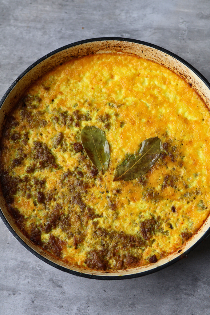 Traditional South African bobotie with golden egg custard topping and bay leaves