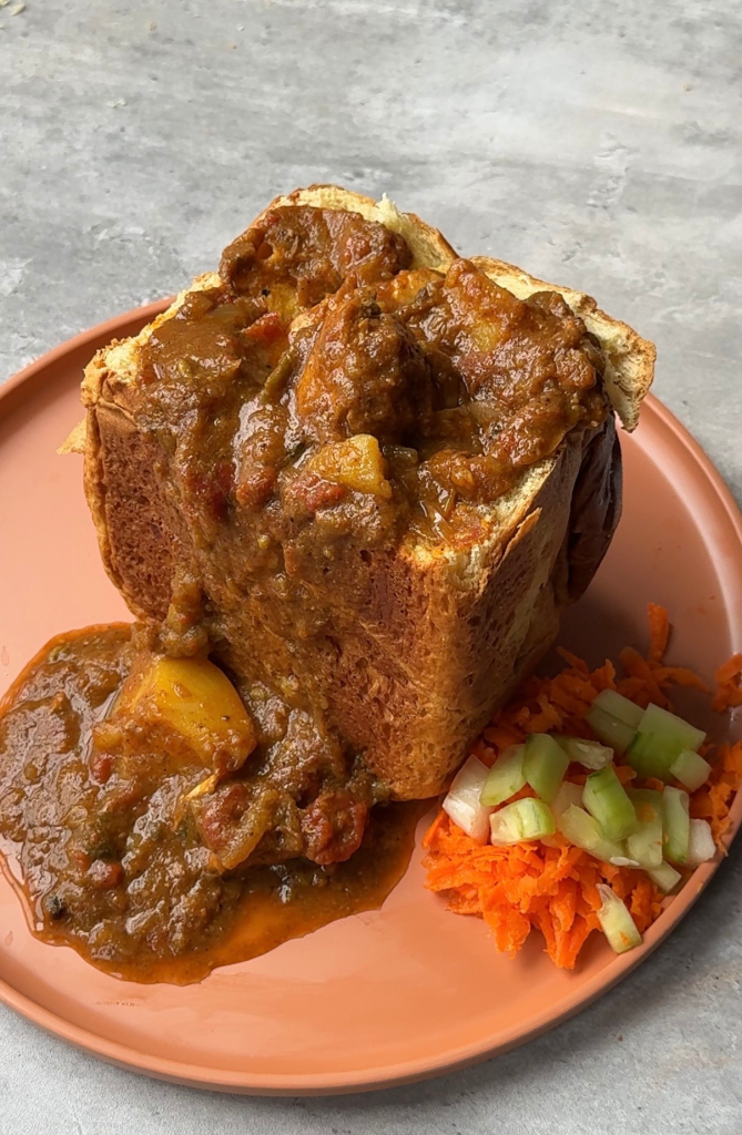 South African bunny chow filled with spicy curry and served with fresh salad