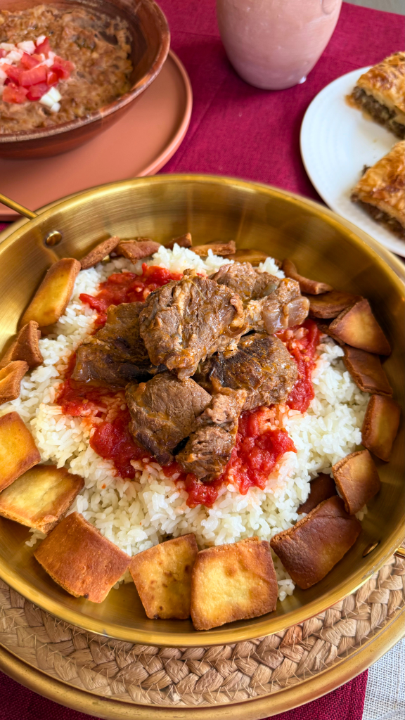 Traditional Egyptian fattah made with rice, toasted bread, tender beef, tomato sauce, and garlic vinegar, served in a golden bowl.