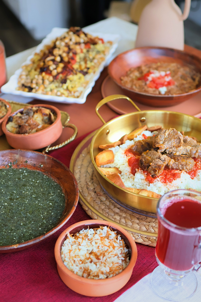 Traditional Egyptian dining table featuring koshari, fattah, molokhia, Egyptian goulash, Om Ali, hibiscus tea, and other classic Egyptian dishes.