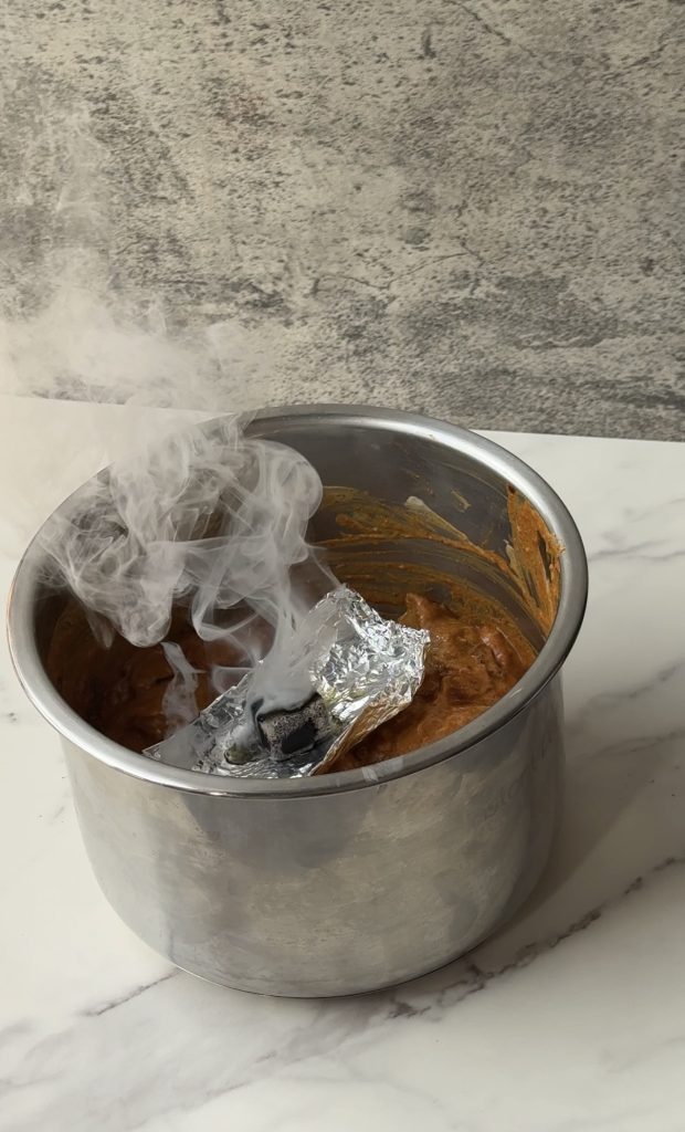 The dhungar smoking method being used to infuse marinated chicken with charcoal smoke for authentic Bangladeshi kacchi biryani.