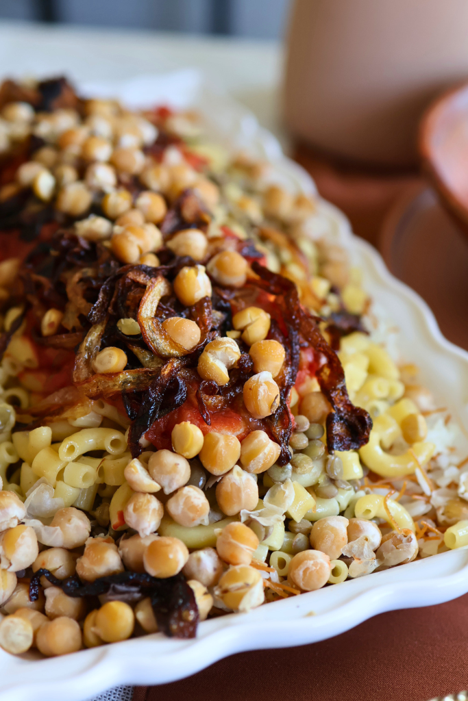 Traditional Egyptian koshari topped with crispy fried onions, chickpeas, lentils, pasta, rice, and tomato sauce.