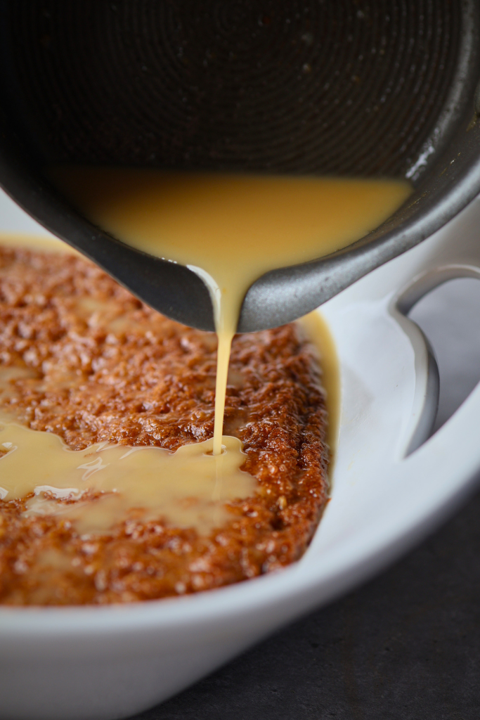 South African malva pudding with warm creamy sauce being poured over the top