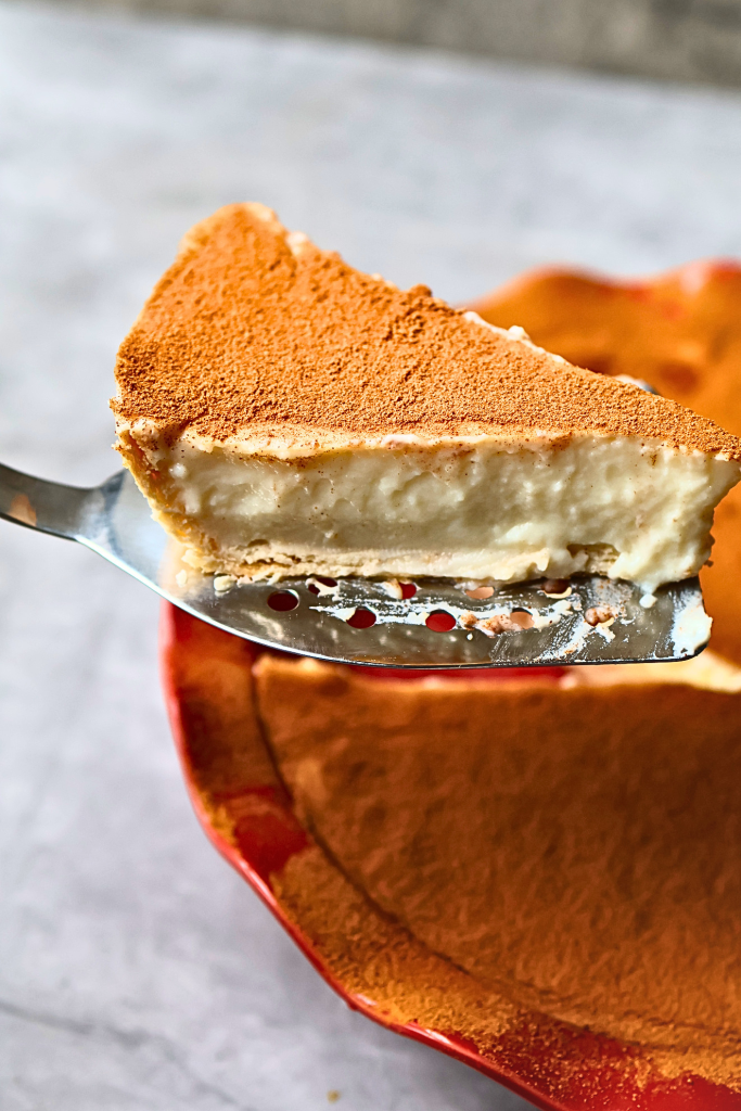 Slice of South African melktert with creamy milk custard filling and cinnamon topping