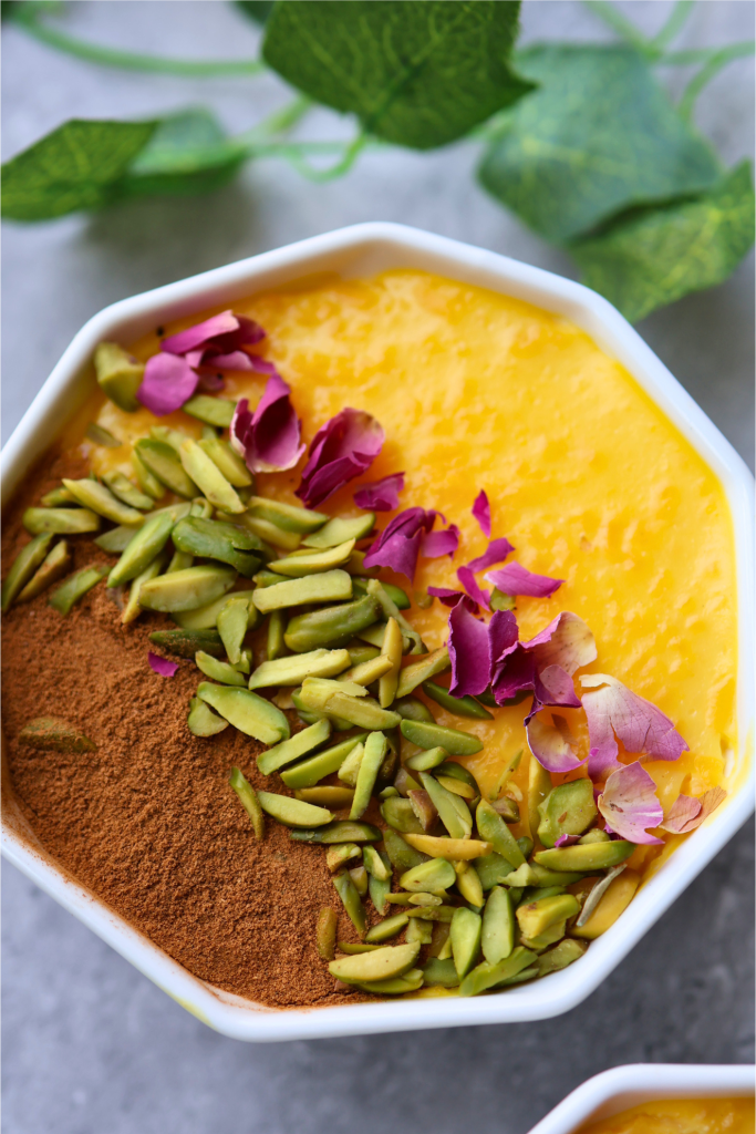Traditional Persian sholeh zard saffron rice pudding decorated with cinnamon, pistachios, and dried rose petals.