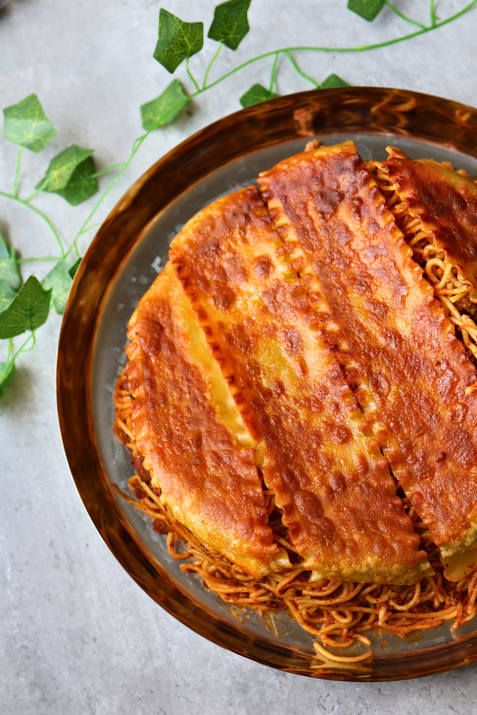 Persian macaroni with crispy golden lasagna sheet tahdig, flipped from the pot to reveal the browned pasta crust.